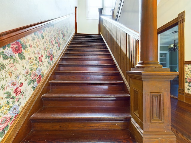 stairs with wood-type flooring and a chandelier