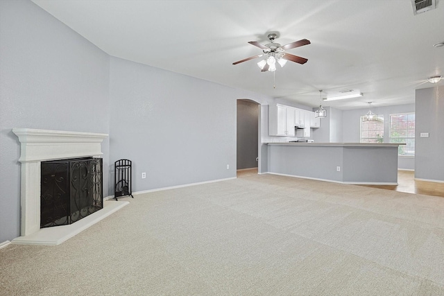 unfurnished living room with ceiling fan with notable chandelier and light carpet