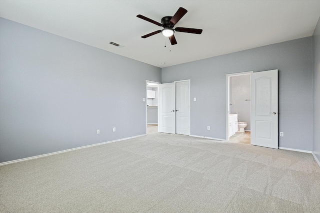 unfurnished bedroom with ceiling fan, a spacious closet, connected bathroom, light colored carpet, and a closet