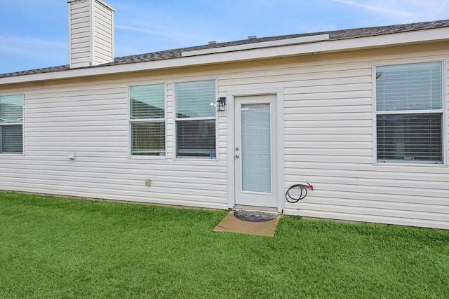 view of exterior entry featuring a lawn