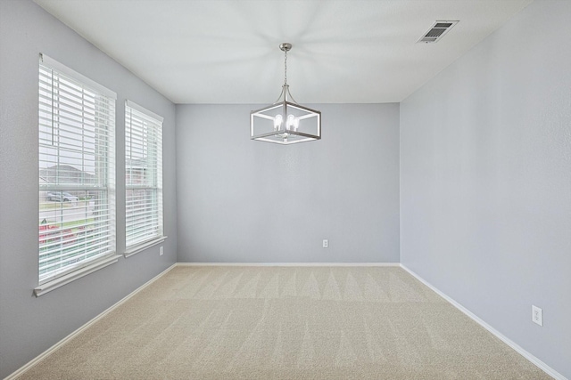 empty room featuring carpet floors and a chandelier