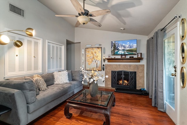 living room featuring a tiled fireplace, lofted ceiling, dark hardwood / wood-style floors, and ceiling fan