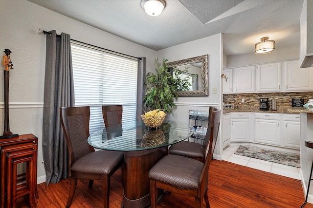 dining space with hardwood / wood-style floors and a textured ceiling