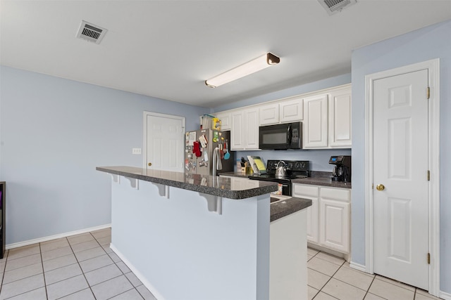 kitchen with light tile patterned floors, a breakfast bar, a center island, black appliances, and white cabinets