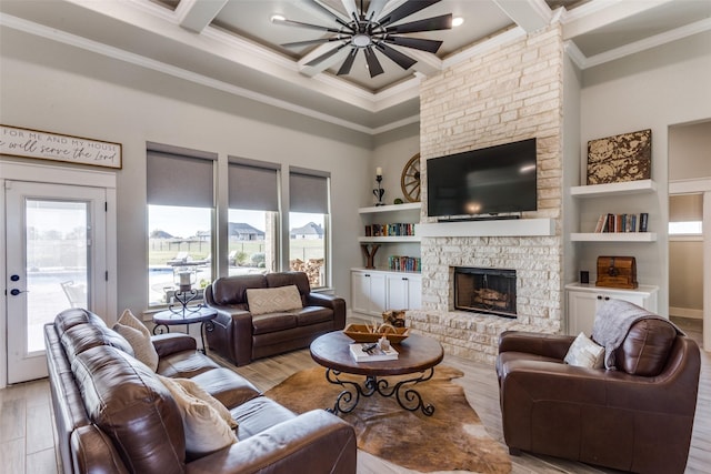 living room featuring a healthy amount of sunlight, a fireplace, light hardwood / wood-style floors, and ornamental molding