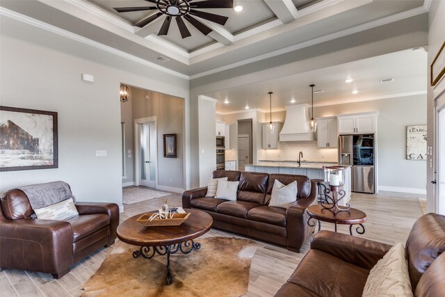 living room with sink, ceiling fan, light wood-type flooring, ornamental molding, and beamed ceiling