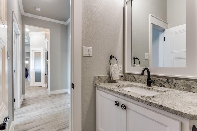 bathroom with crown molding, vanity, and hardwood / wood-style flooring