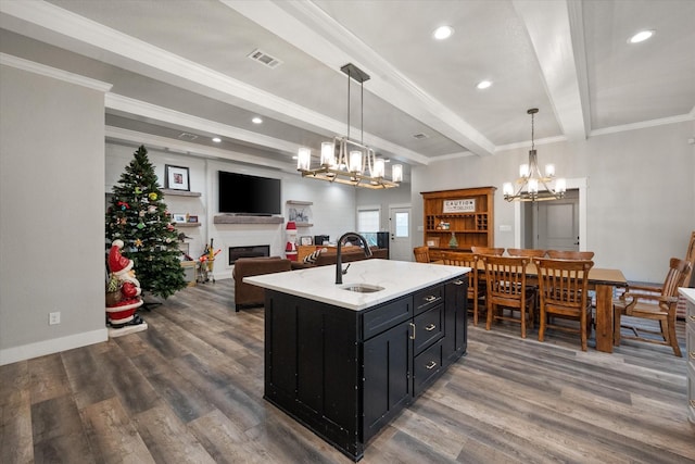 kitchen with beamed ceiling, dark hardwood / wood-style flooring, a kitchen island with sink, and hanging light fixtures