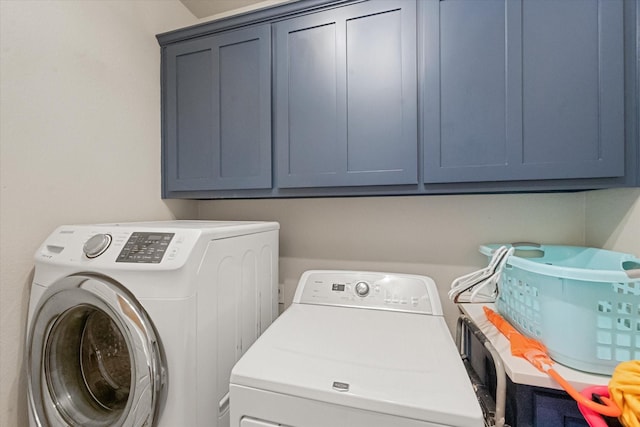 clothes washing area with cabinets and washer and dryer