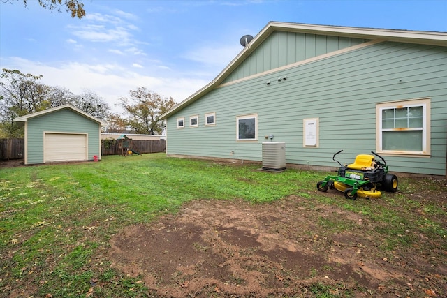 rear view of house featuring a garage, an outdoor structure, a yard, and central AC unit