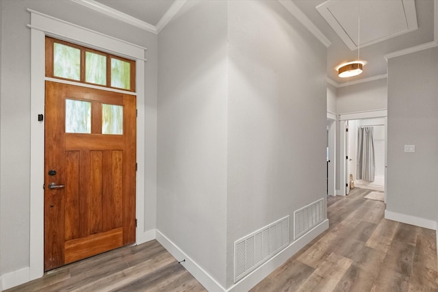 foyer with ornamental molding and hardwood / wood-style floors