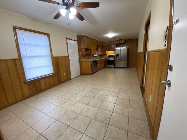 kitchen featuring ceiling fan, light tile patterned floors, wood walls, and appliances with stainless steel finishes