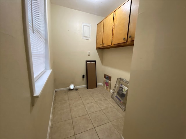 washroom with electric dryer hookup, electric panel, light tile patterned floors, and cabinets