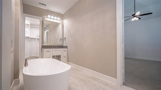 bathroom with ceiling fan, a tub to relax in, and vanity