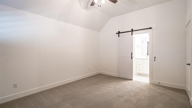 empty room with ceiling fan, a barn door, lofted ceiling, and light carpet