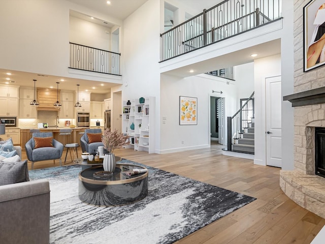 living room featuring hardwood / wood-style flooring, ceiling fan, and a stone fireplace