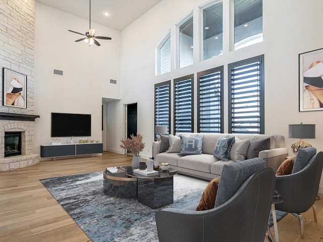 living room featuring hardwood / wood-style floors, a stone fireplace, and ceiling fan