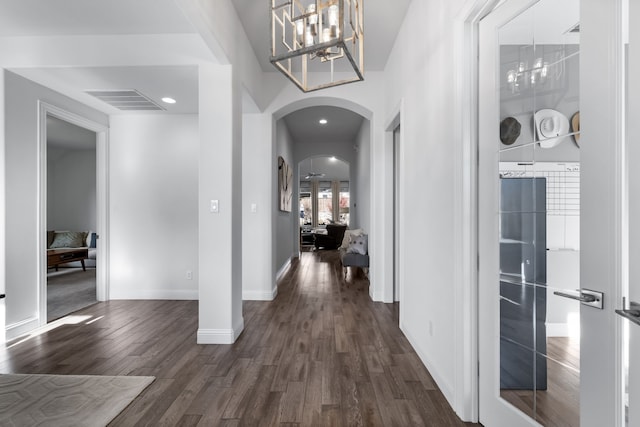 hallway featuring dark wood-type flooring and a notable chandelier