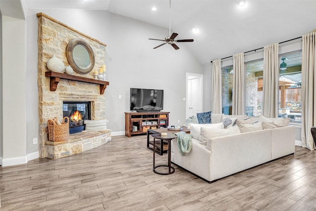 living room featuring a fireplace, light hardwood / wood-style flooring, high vaulted ceiling, and ceiling fan