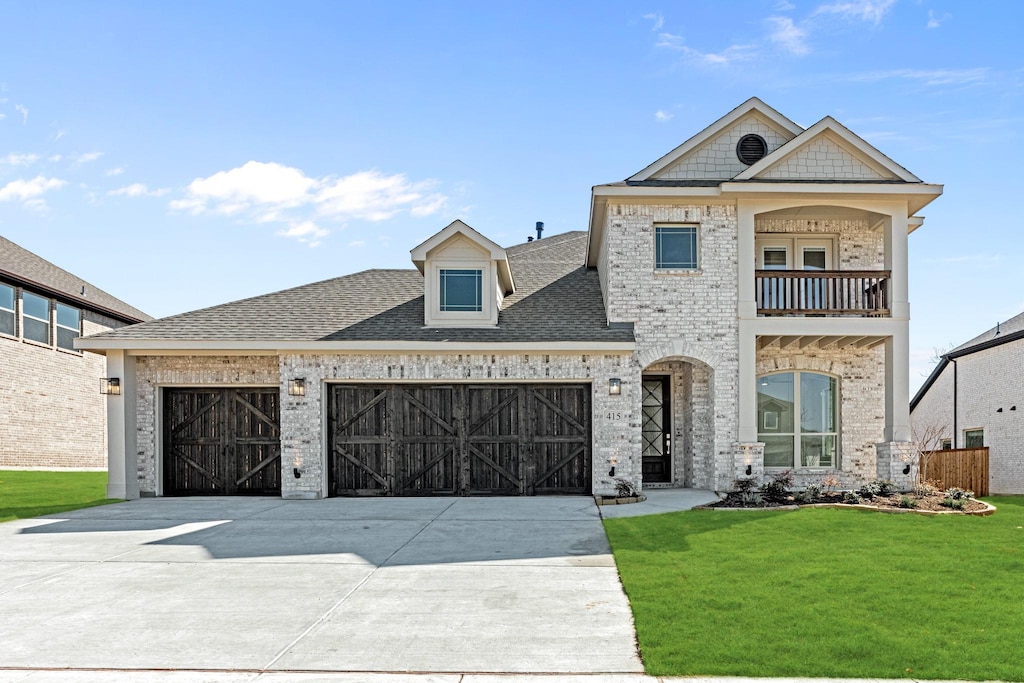 view of front facade featuring an attached garage, a balcony, brick siding, driveway, and a front yard