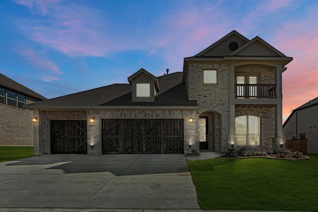 view of front facade with a balcony, a garage, brick siding, concrete driveway, and a front lawn