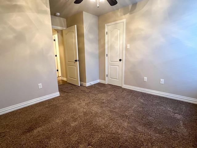 spare room featuring dark colored carpet and ceiling fan