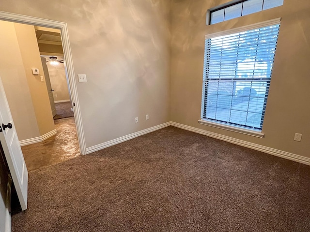 spare room with dark colored carpet and ceiling fan