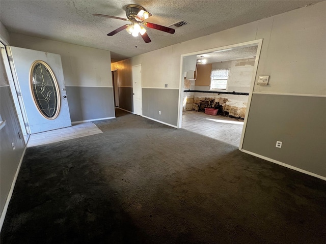 interior space with carpet, ceiling fan, and a textured ceiling