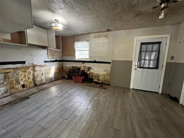 kitchen with white cabinets, ceiling fan, light wood-type flooring, and a textured ceiling