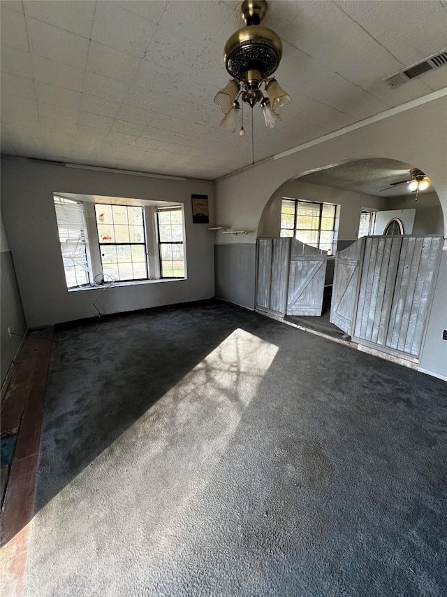 interior space with ceiling fan and dark colored carpet