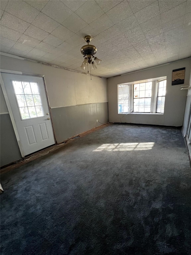 empty room featuring dark carpet, a wealth of natural light, and ceiling fan