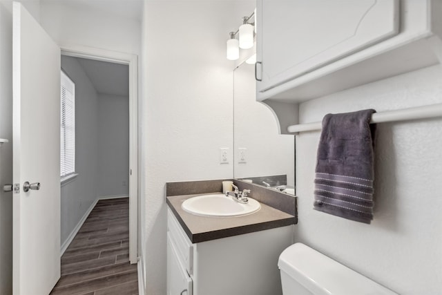 bathroom with toilet, vanity, and hardwood / wood-style flooring