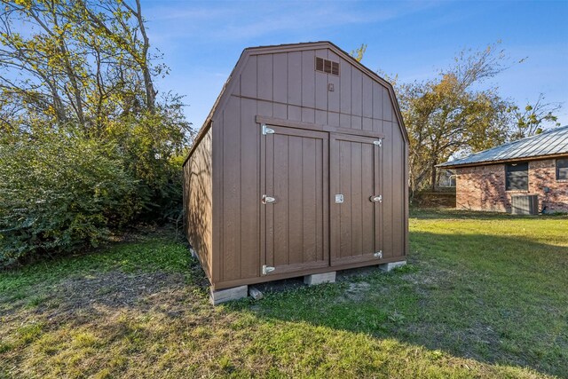 view of outdoor structure featuring a lawn and central AC