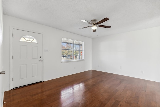 foyer entrance with a textured ceiling, ceiling fan, and dark wood-type flooring