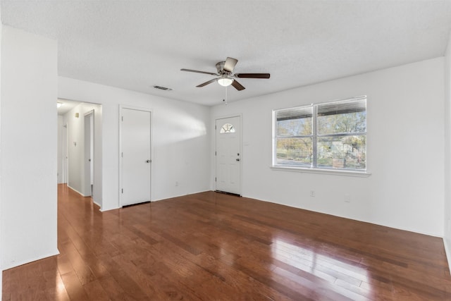 empty room with ceiling fan, dark hardwood / wood-style flooring, and a textured ceiling