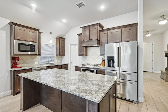 kitchen featuring lofted ceiling, sink, hanging light fixtures, a kitchen island, and stainless steel appliances