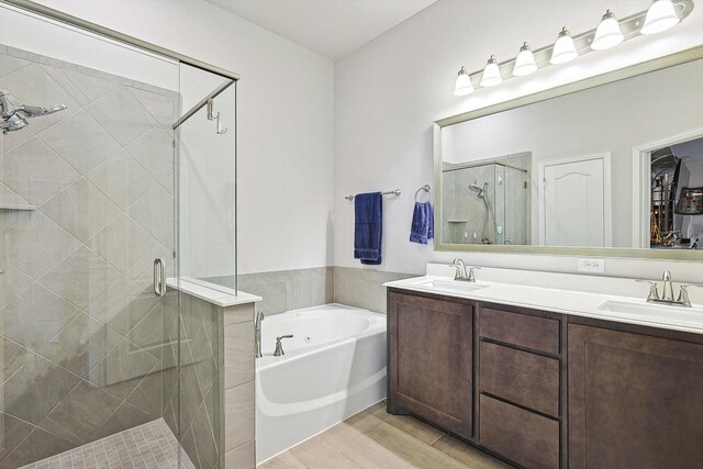 bathroom with hardwood / wood-style flooring, vanity, and separate shower and tub