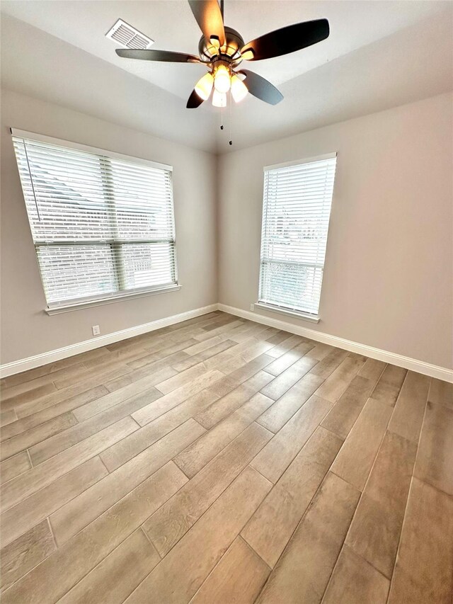 empty room with ceiling fan and light hardwood / wood-style floors