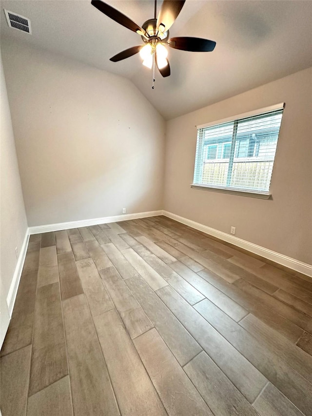 empty room featuring hardwood / wood-style floors, vaulted ceiling, and ceiling fan