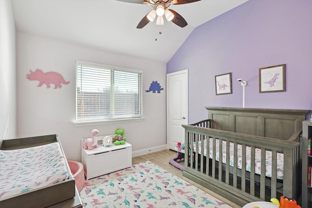 bedroom featuring a nursery area, ceiling fan, vaulted ceiling, and light wood-type flooring