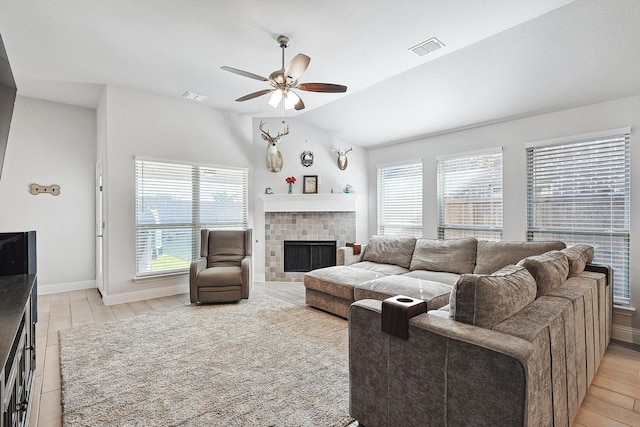 living room with light hardwood / wood-style flooring, a brick fireplace, vaulted ceiling, and ceiling fan