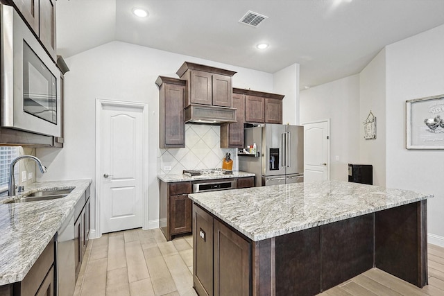 kitchen with light stone counters, sink, a center island, and appliances with stainless steel finishes