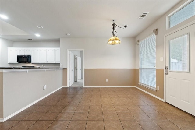 kitchen featuring decorative light fixtures, white cabinets, tile patterned floors, and a healthy amount of sunlight