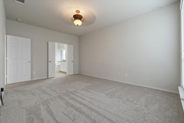 unfurnished bedroom with ensuite bath, ceiling fan, and light carpet