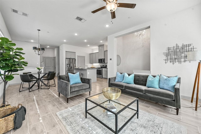 living room with ceiling fan with notable chandelier and light wood-type flooring