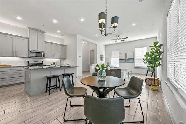 dining area featuring ceiling fan with notable chandelier and light hardwood / wood-style floors