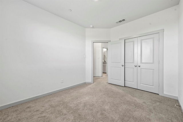 unfurnished bedroom featuring light carpet and a closet