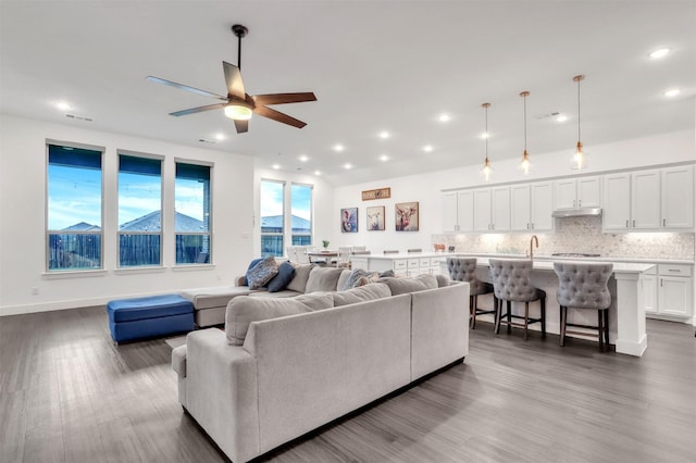 living room featuring sink, hardwood / wood-style floors, and ceiling fan