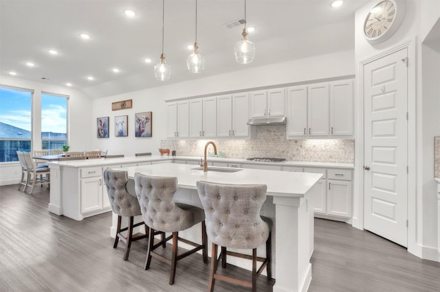 kitchen with sink, white cabinetry, a kitchen island with sink, and a kitchen bar