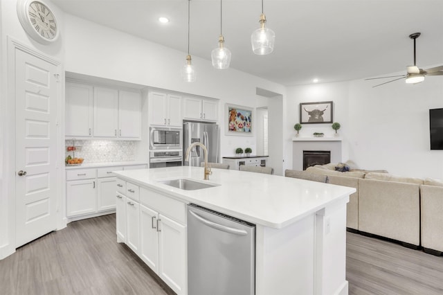 kitchen featuring sink, an island with sink, appliances with stainless steel finishes, and white cabinetry